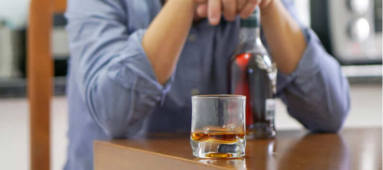 Детоксикация алкоголиков: мужчина облокотился на бутылку 